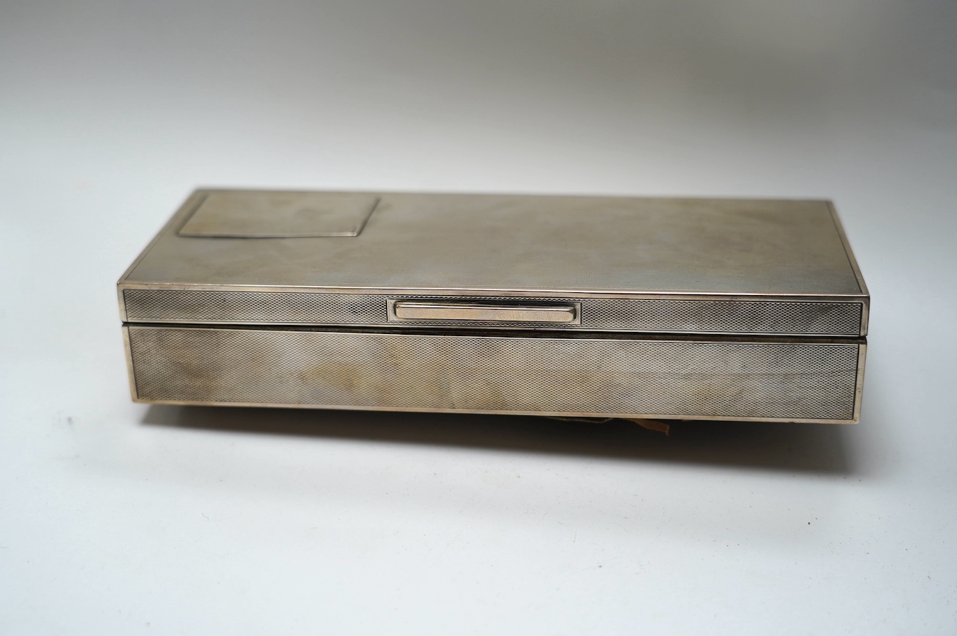 A George V engine turned silver mounted rectangular cigarette box, London, 1935, 21.7cm. Condition - poor